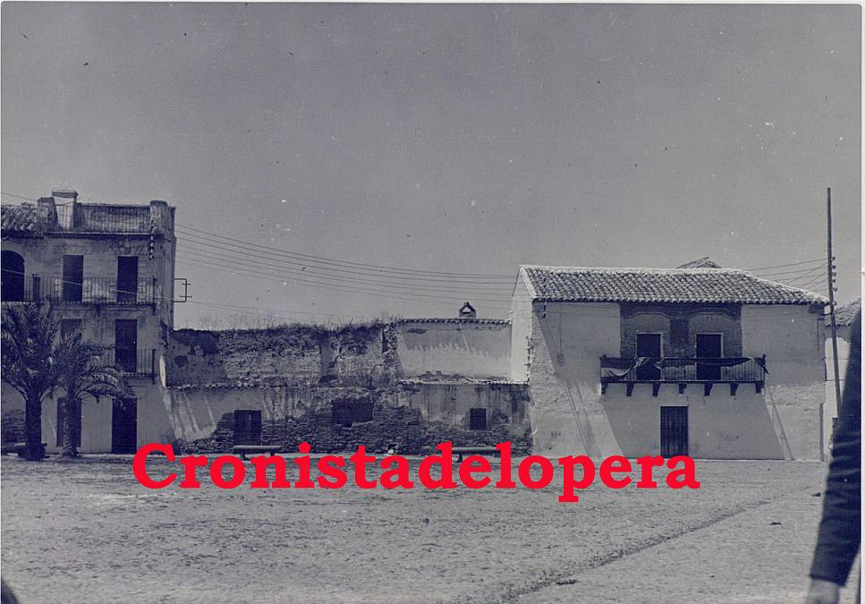 Paseo vespertino por la Plaza del Ayuntamiento de Lopera en 1941. Detalle de las fachadas de las casas y las dos palmeras de la izquierda.