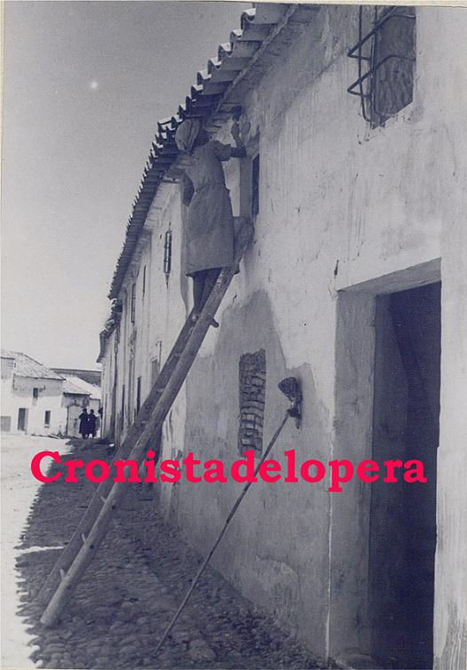 Paseo matinal por la calle del Pilar de Lopera de la mano de una loperana encalando la fachada de su casa en 1941