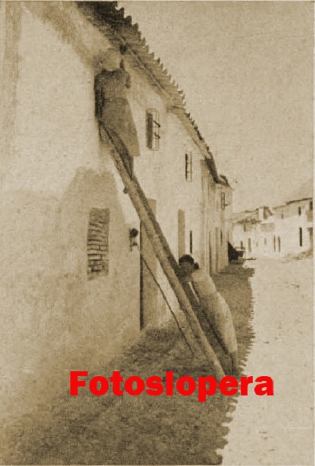 Paseo vespertino por la calle del Pilar de Lopera de la mano de dos loperanas encalando la fachada de su casa en 1942.