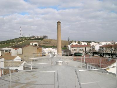 Una vista del Cerro y parte de la Barriada de San Cristóbal desde los depósitos de aceite de la Cooperativa Oleícola La Loperana. Detalle de la chimenea de la cooperativa.