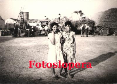 Conchi Bellido y Helga Walter en el Cortijo de los Morrones. Al fondo cargando las mieses en los remolques de los tractores. Año 1959