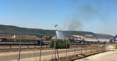 Labores de extinción de un incendio en un rastrojo junto a la A4 (a unos 100 metros de la gasolinera de Los Caballos) con un helicóptero. Foto Víctor Ansino